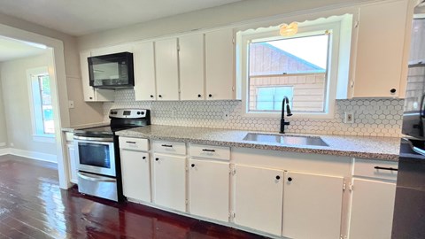 a kitchen with white cabinets and a sink and a window