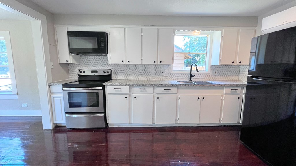 an empty kitchen with white cabinets and black appliances