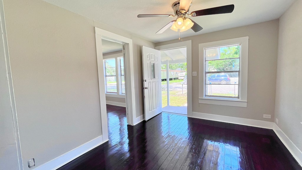 an empty living room with a ceiling fan