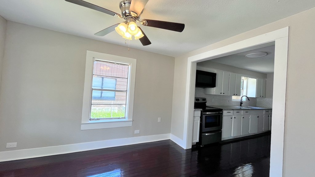 an empty living room and kitchen with a ceiling fan