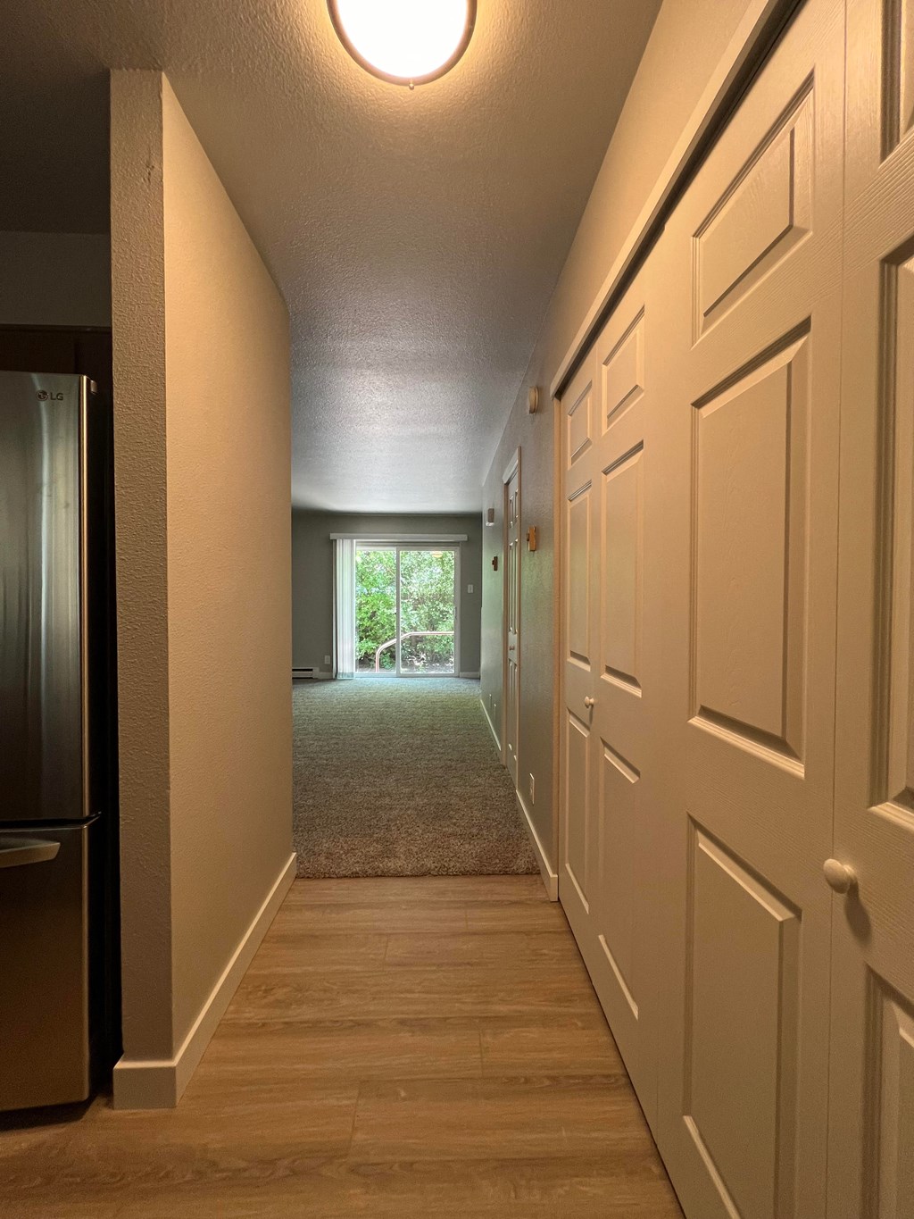a hallway with white doors and a door to a living room