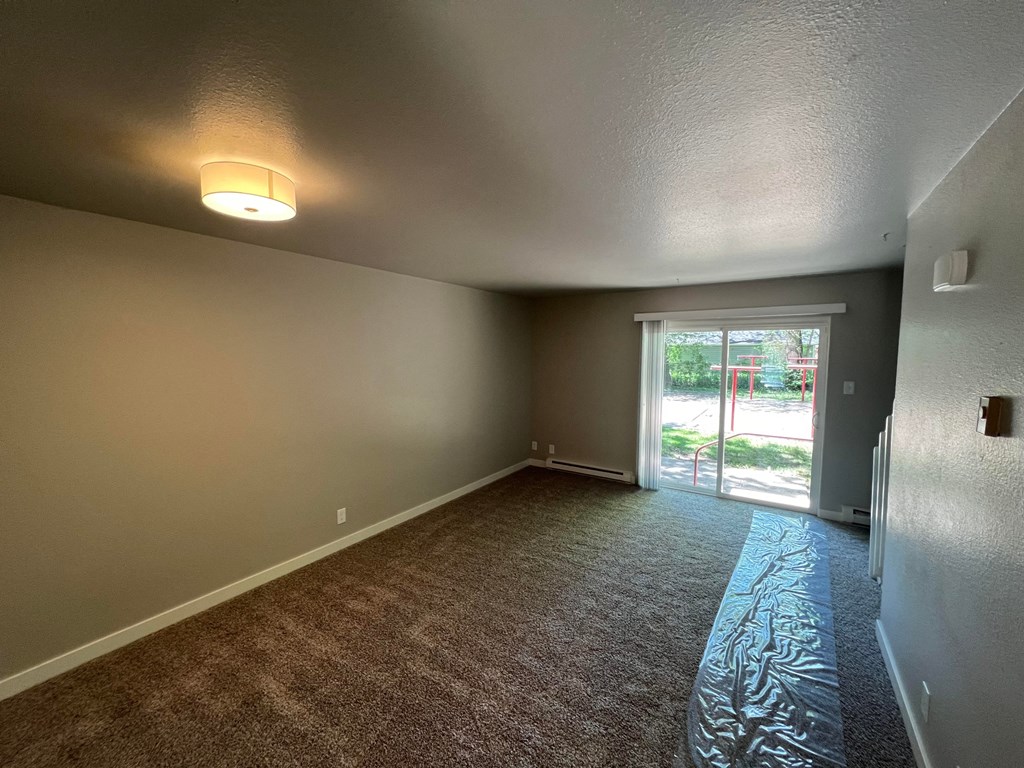 an empty living room with a sliding glass door to a patio