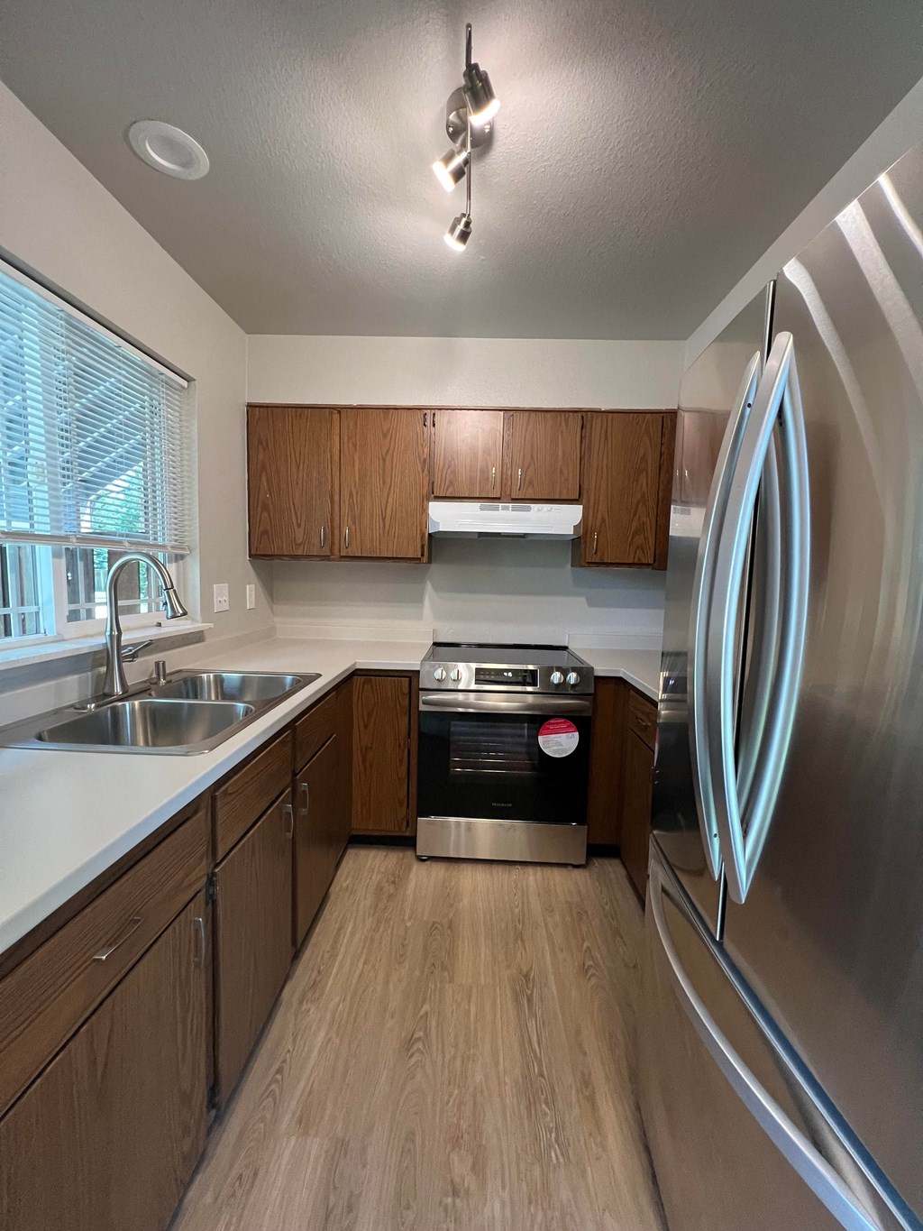 an empty kitchen with stainless steel appliances and wooden cabinets