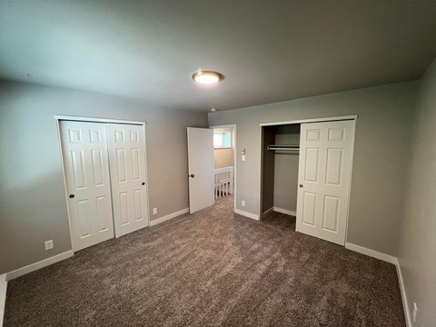 a bedroom with two closets and a carpeted floor
