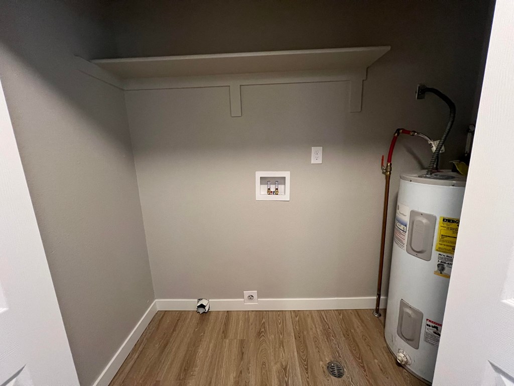 a room with a water heater and a wall with a dryer