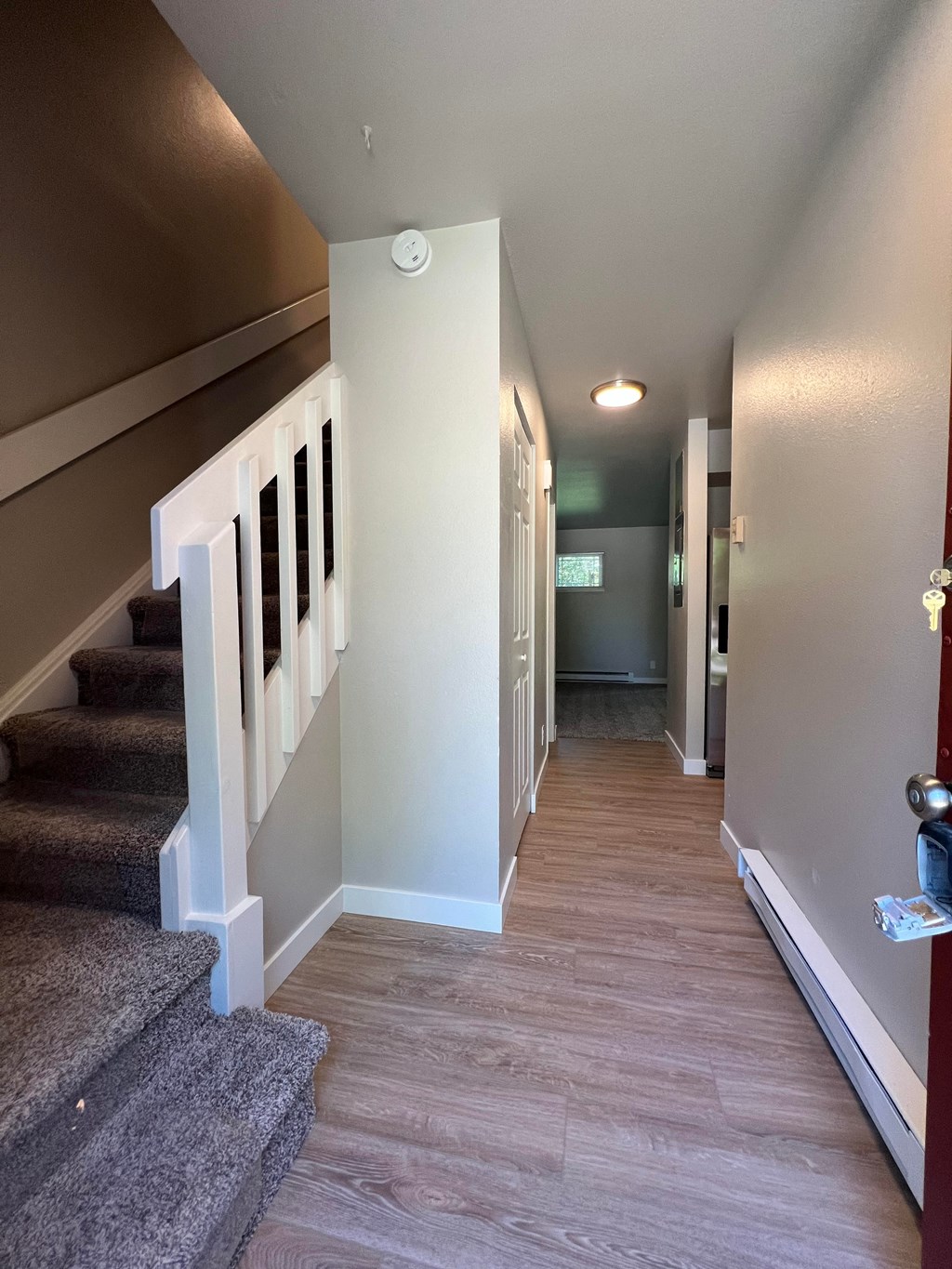 a look down the hallway of a house with stairs and a hallway with carpeting