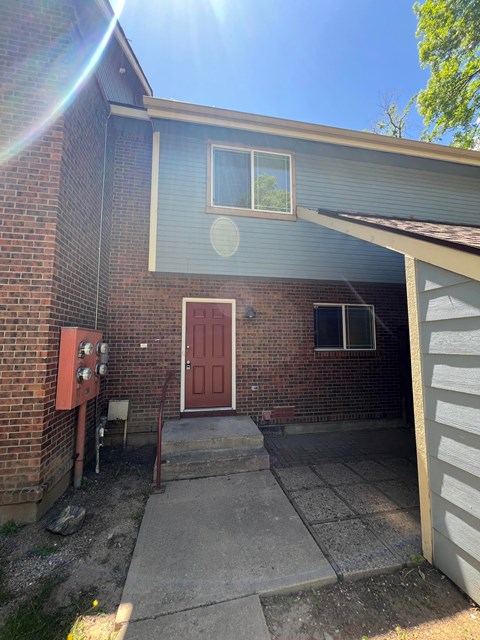 the front of a brick house with a red door