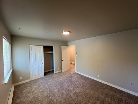 a empty living room with carpet and a door to a closet