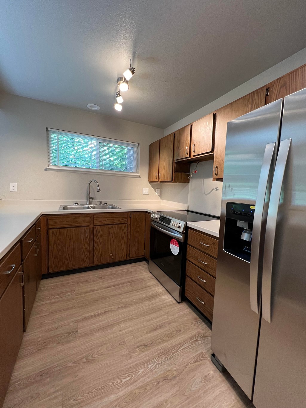 an empty kitchen with stainless steel appliances and wooden cabinets