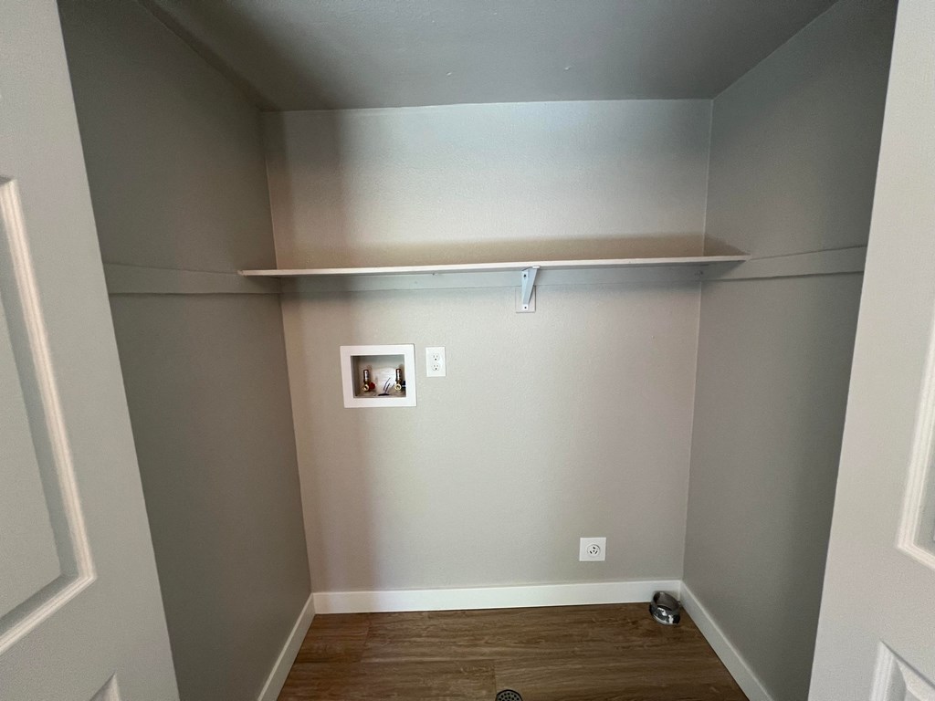 a room with a shelf on the wall and a wood floor