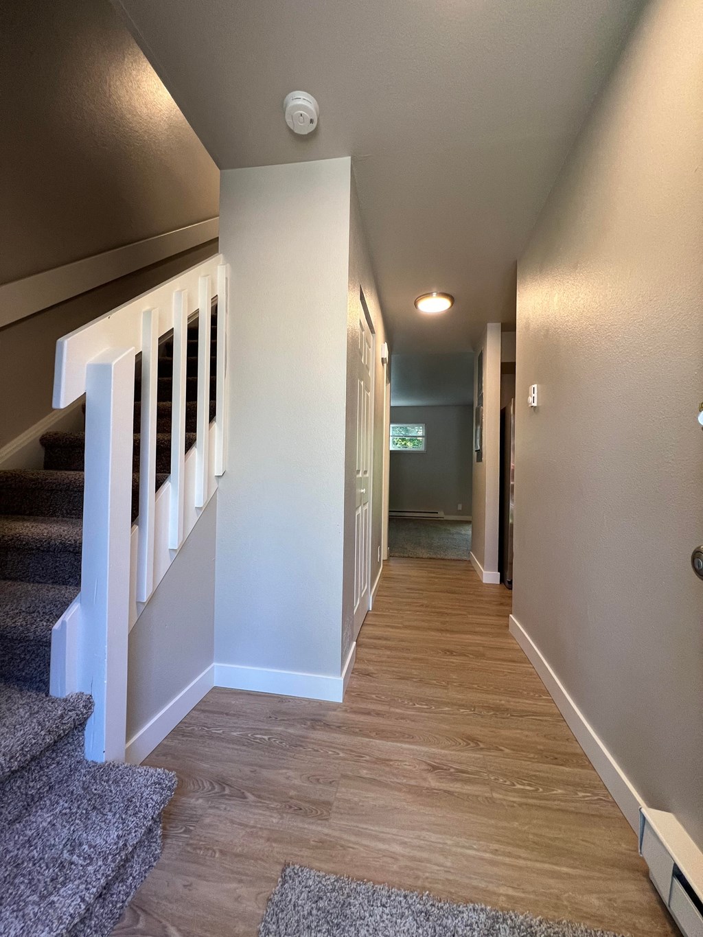 a view down the hallway of a house with stairs and carpeting