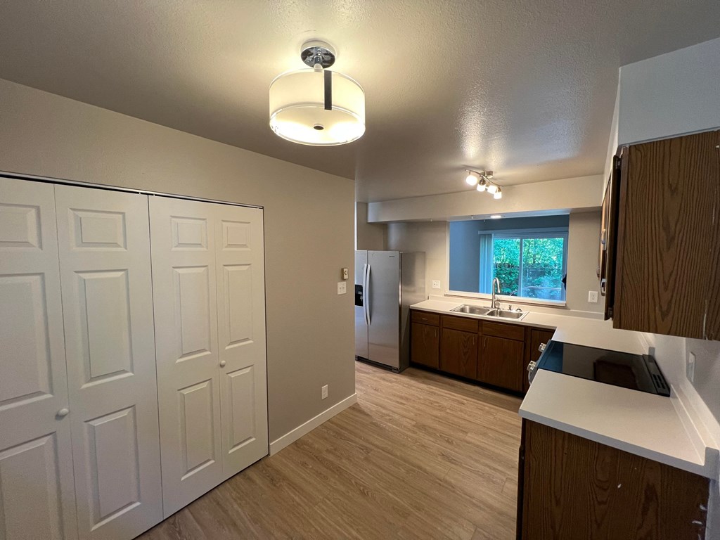 a kitchen with white cabinets and wood floors and a white refrigerator