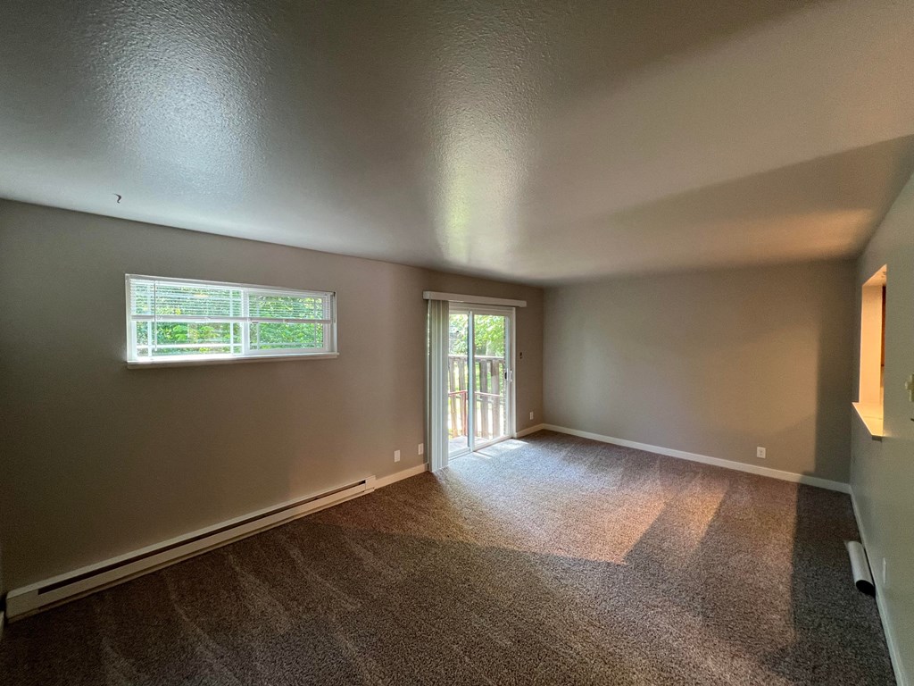 an empty living room with gray walls and a window