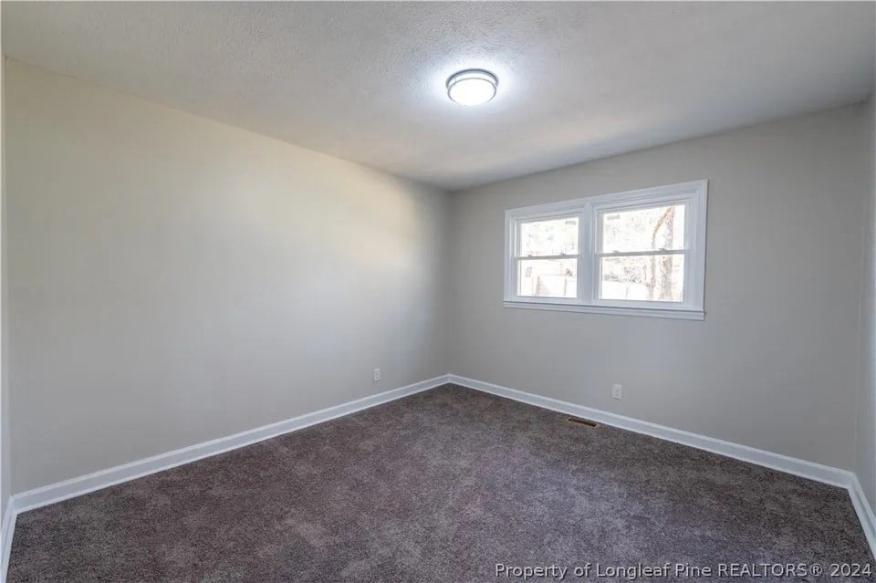 a empty bedroom with a window and carpet