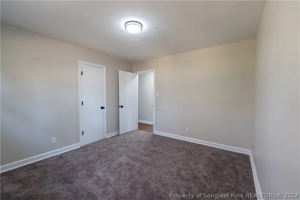 an empty living room with carpet and white walls
