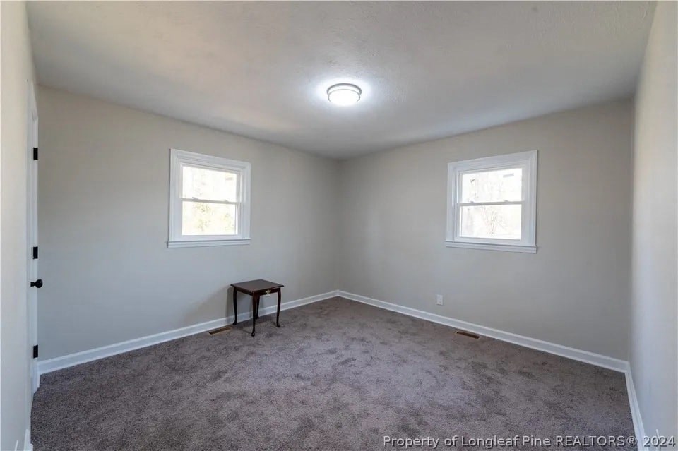 an empty room with a table and two windows