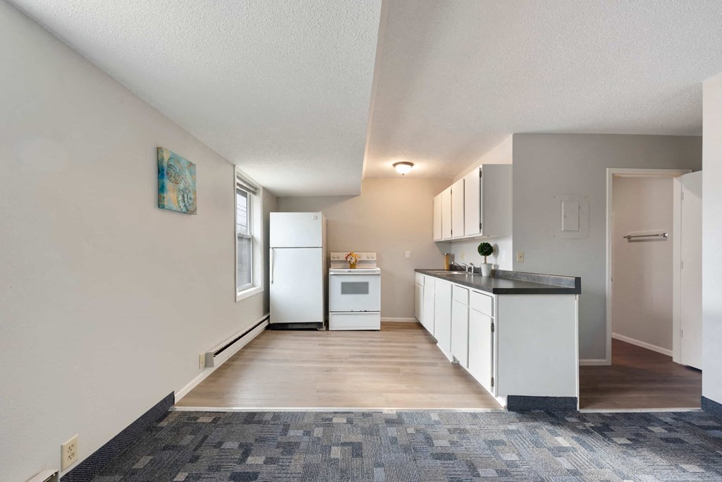 a kitchen with white cabinets and a counter top and a refrigerator