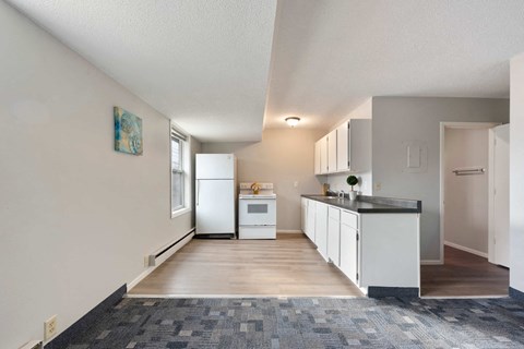 a kitchen with white cabinets and a counter top and a refrigerator