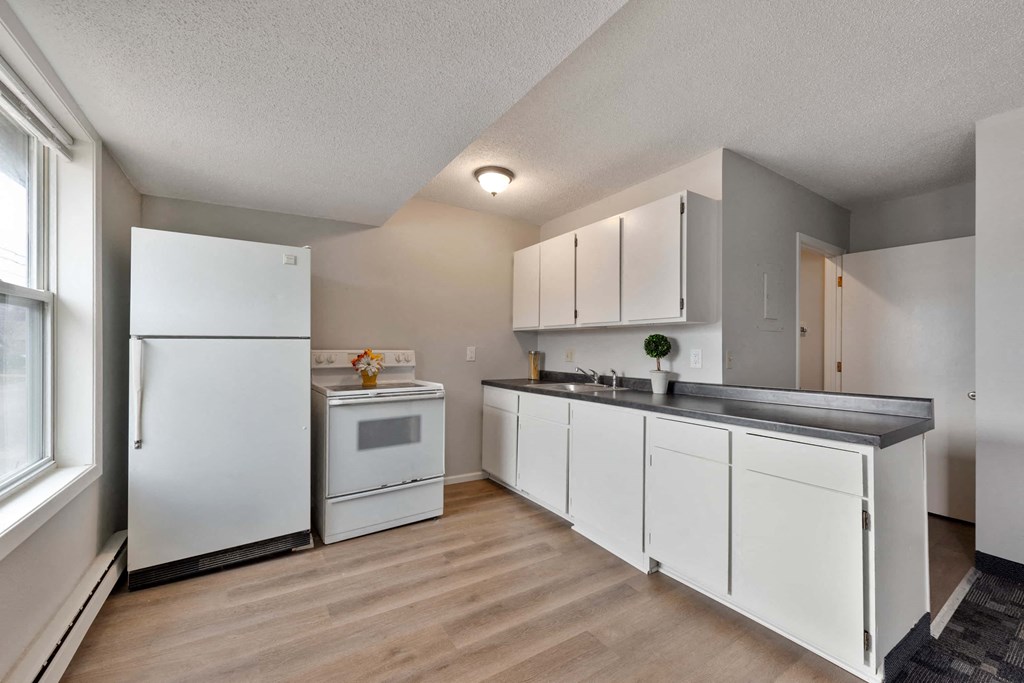 a kitchen with white cabinets and appliances and a window