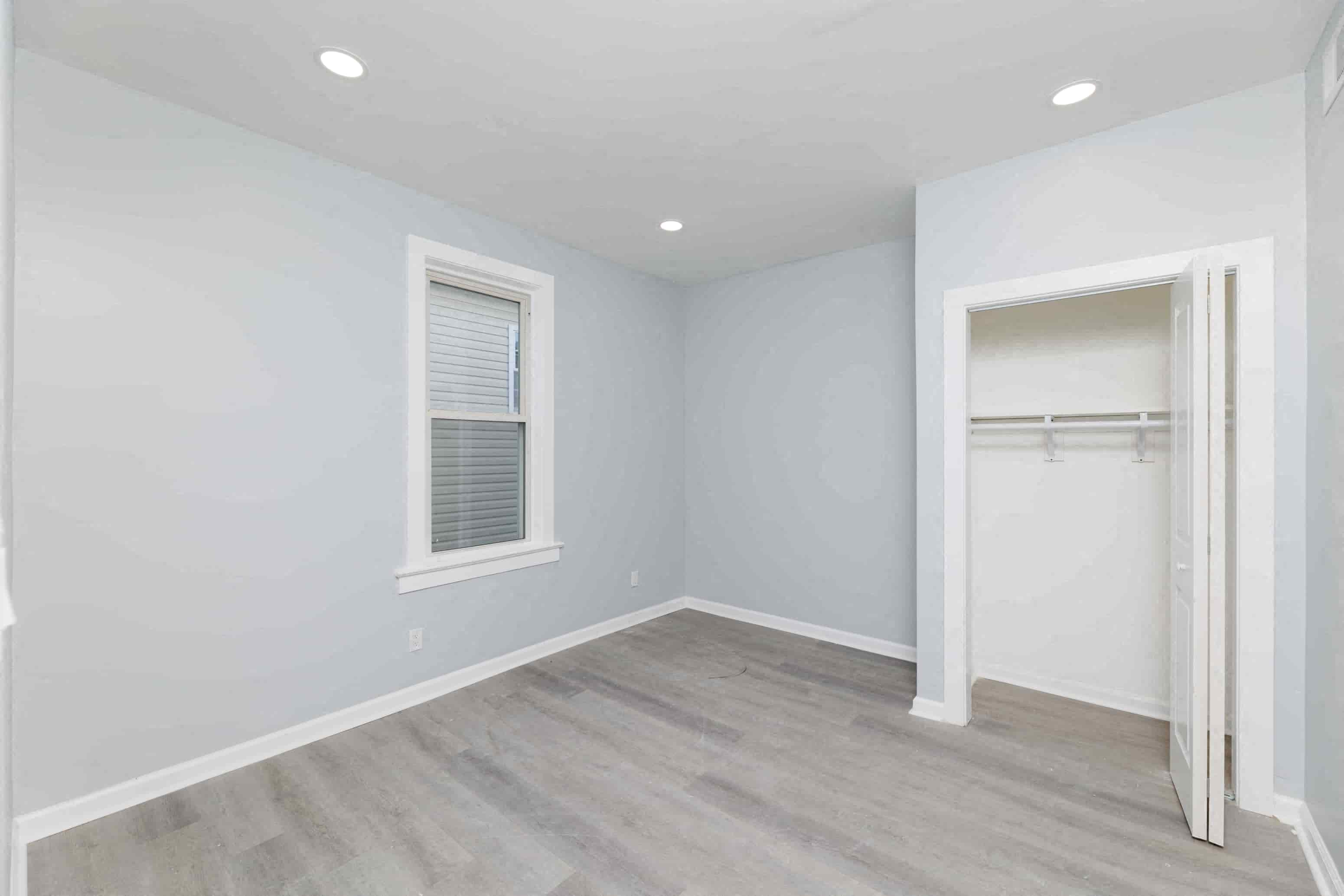 an empty bedroom with a closet and a window