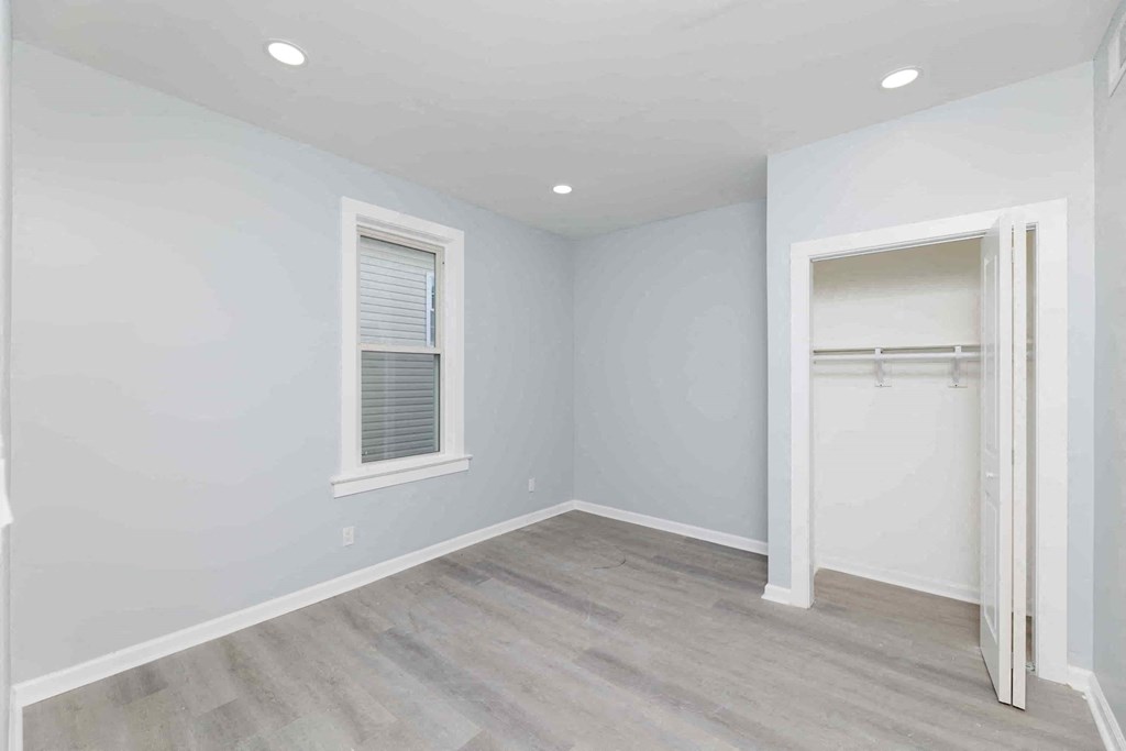 an empty bedroom with a closet and a window