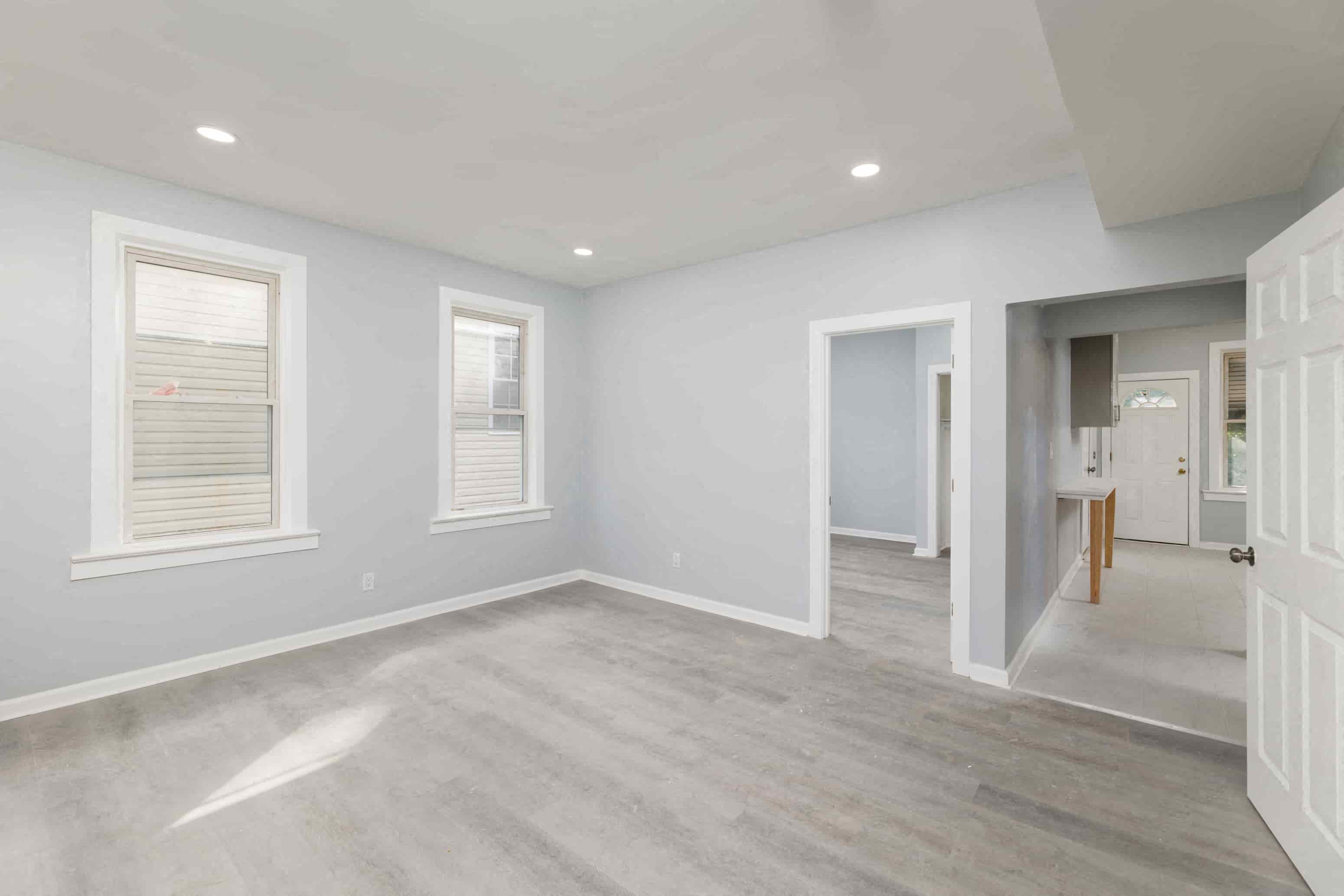 an empty living room with white walls and a white door and window