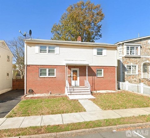 the front of a brick house with a yard and stairs