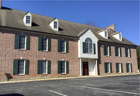 A red brick building with green shutters and a white trim.
