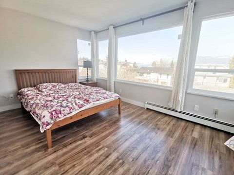 a bedroom with a bed and large windows