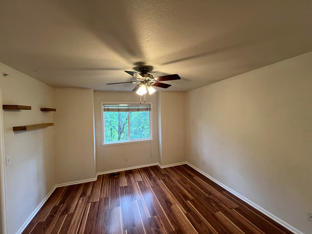 an empty living room with wooden floors and a ceiling fan