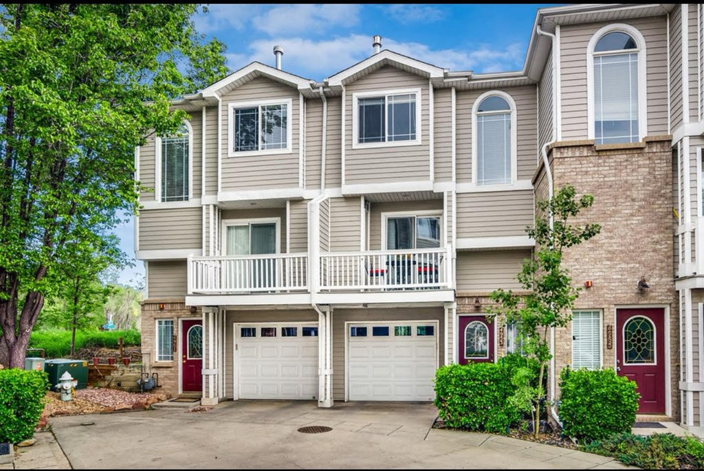 the front of a house with two garage doors and a balcony