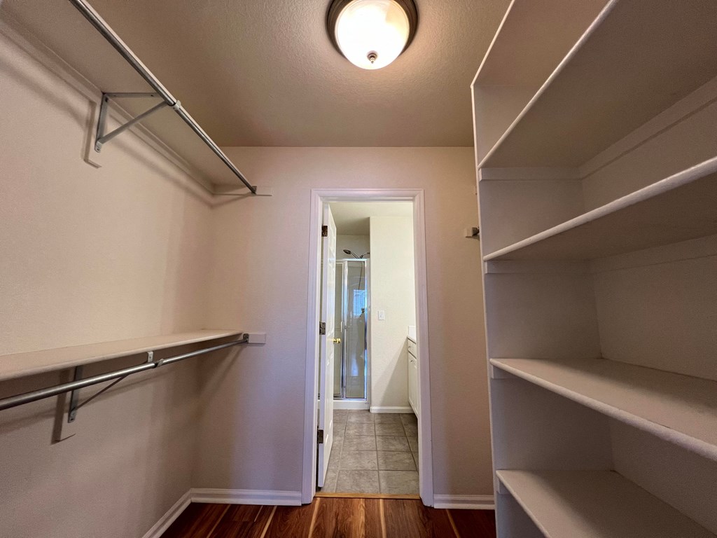 a walk in closet with empty shelves and a hallway with a doorway