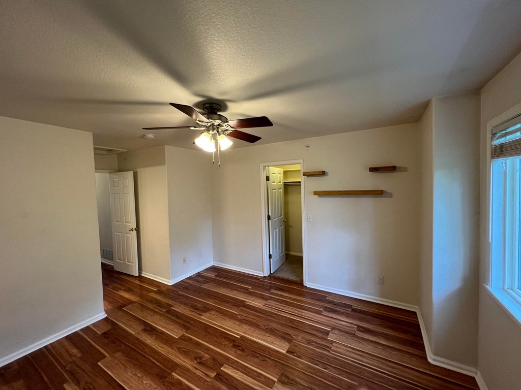 an empty living room with wood floors and a ceiling fan