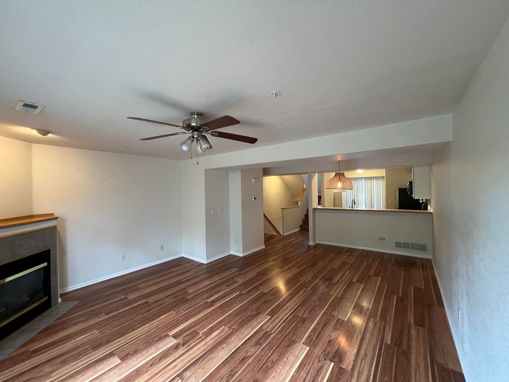 an empty living room with wood flooring and a ceiling fan