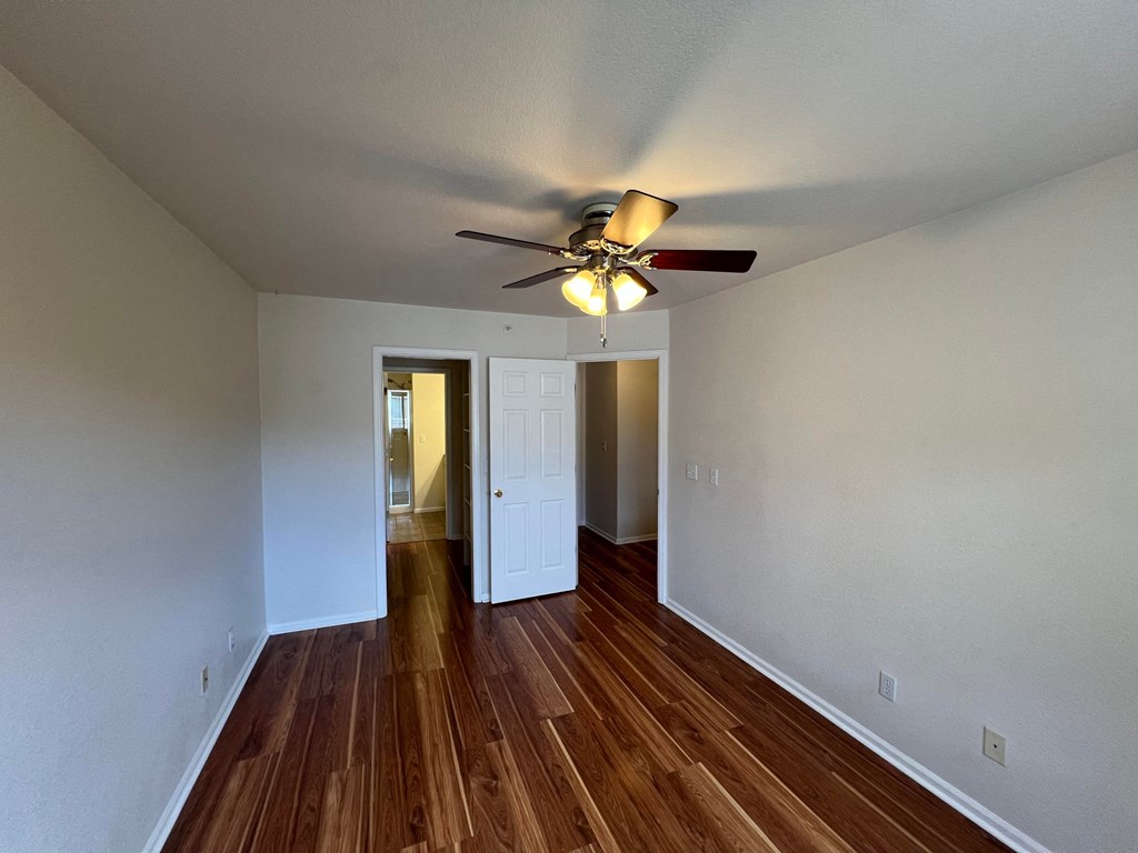 an empty living room with a ceiling fan and wood floors
