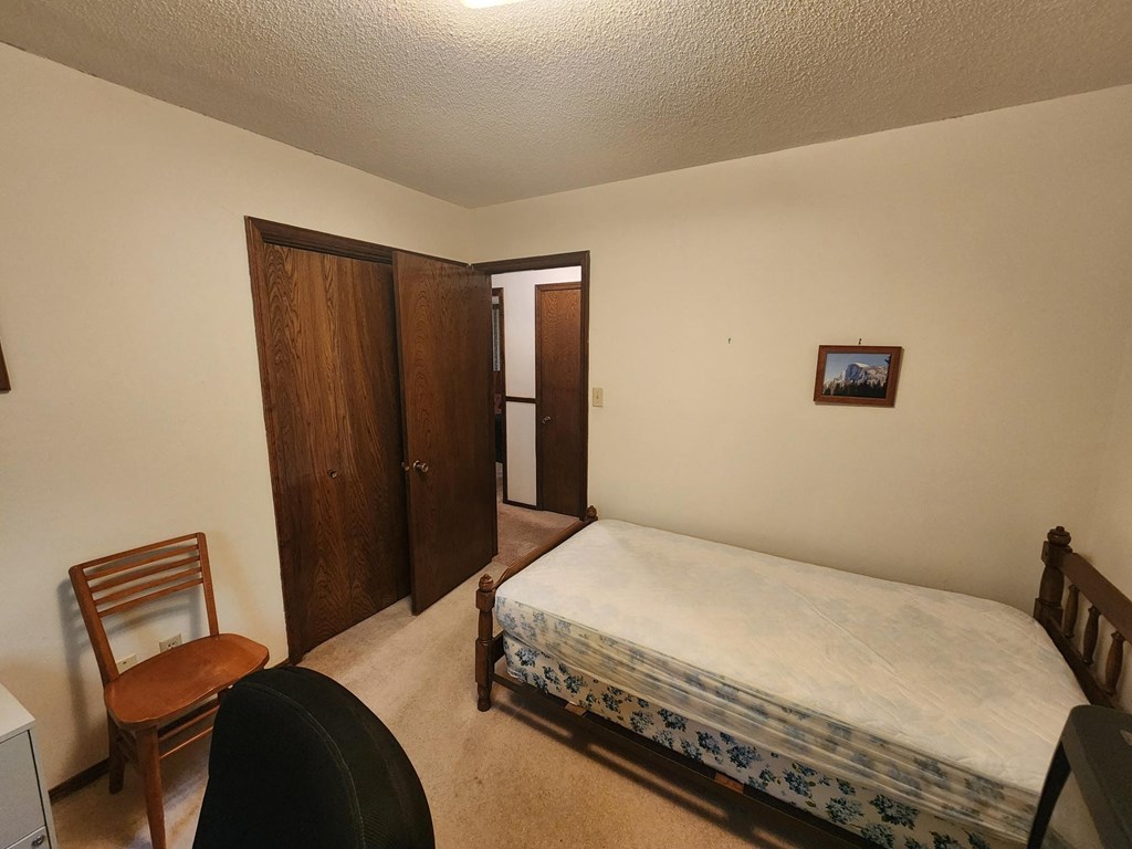 a bedroom with a bed and a chair and a closet