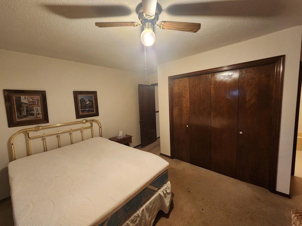 a bedroom with a bed and a ceiling fan and a closet