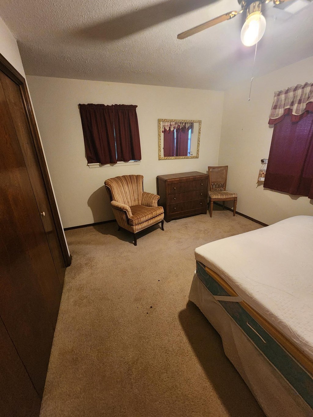 a bedroom with a bed and two chairs and a dresser