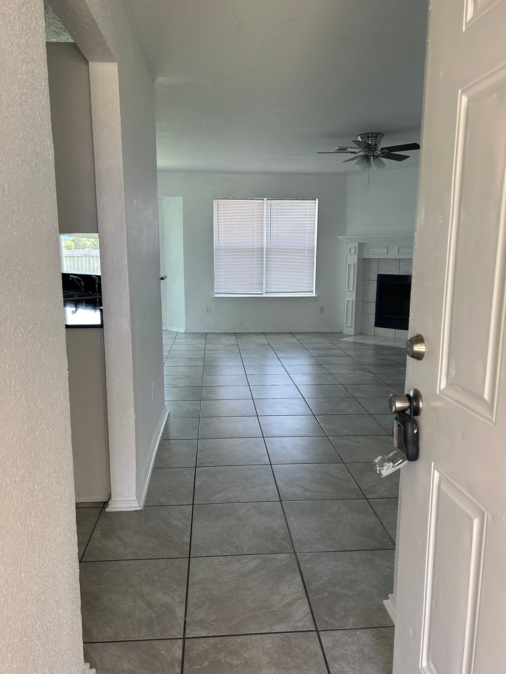 an empty living room with a tile floor and a ceiling fan