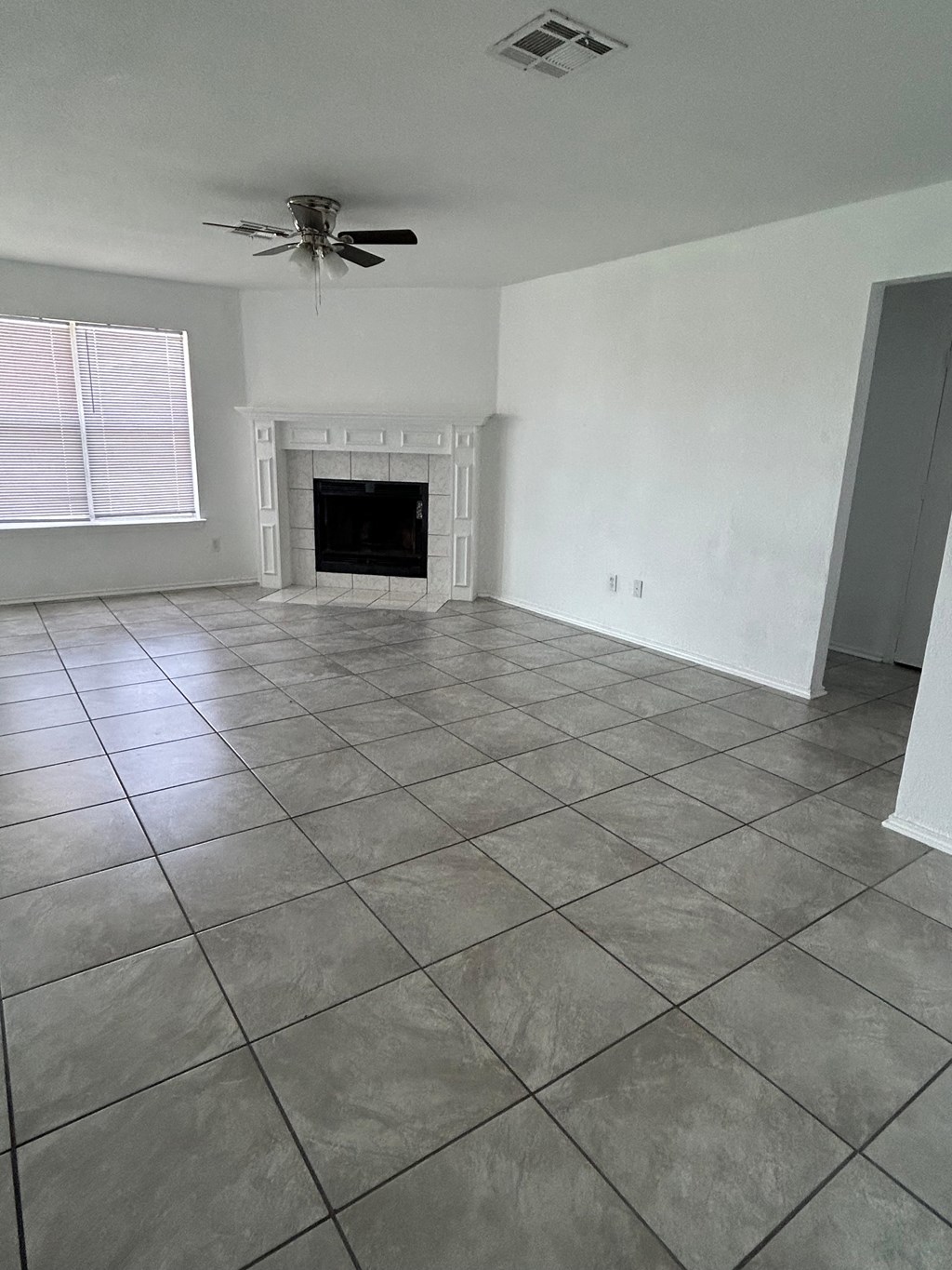 an empty living room with tiled flooring and a fireplace