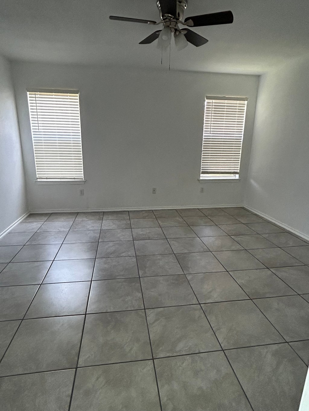 an empty living room with a ceiling fan and tiled floor