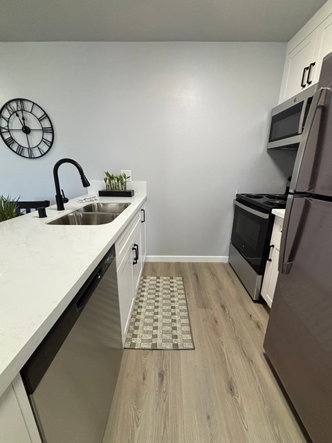 A kitchen with a white counter top and a stainless steel refrigerator.