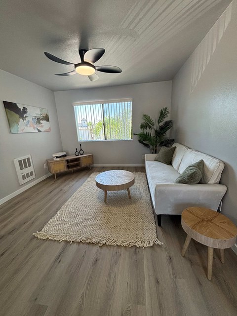 A living room with a white couch, a wooden coffee table, and a ceiling fan.