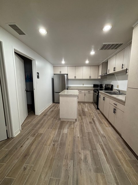 A kitchen with white cabinets and a wooden floor.