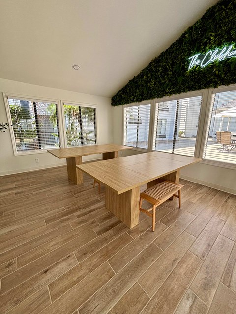 A room with a wooden table and bench with a green plant on the wall.