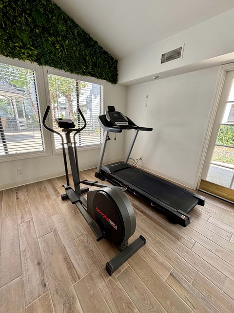 A room with a treadmill and a stationary bike.