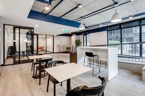 a communal area with tables and chairs in a modern office space