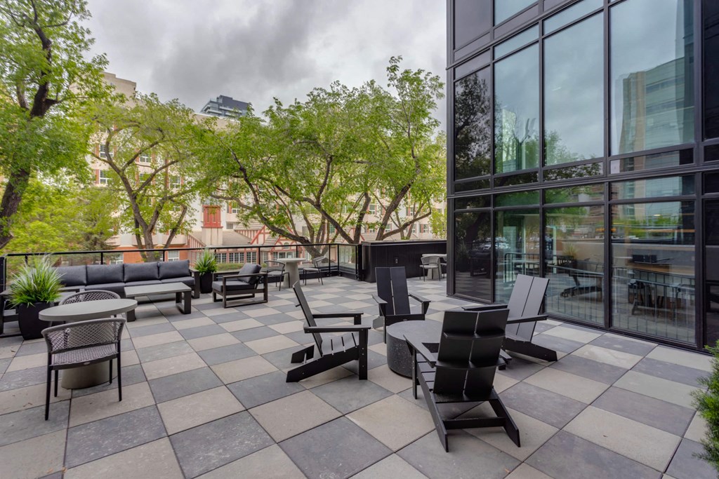 an outdoor patio with tables and chairs and a building with large windows