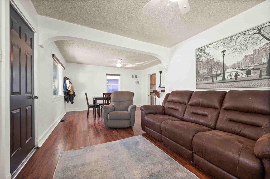 a living room with a leather couch and a chair in front of a dining room