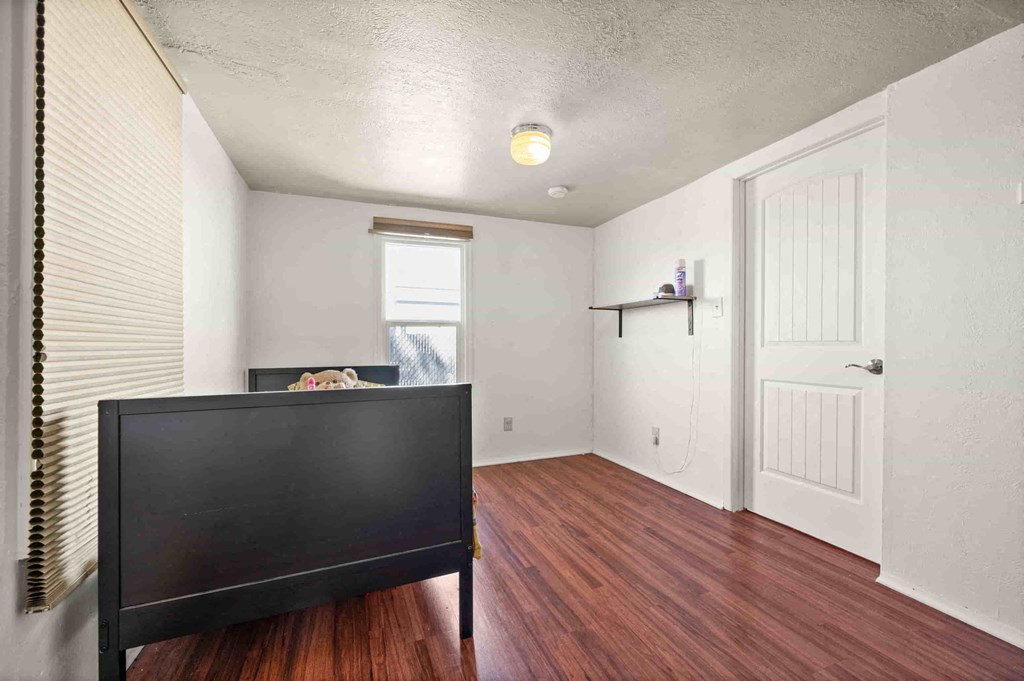 an empty living room with a tv and a door to a bedroom